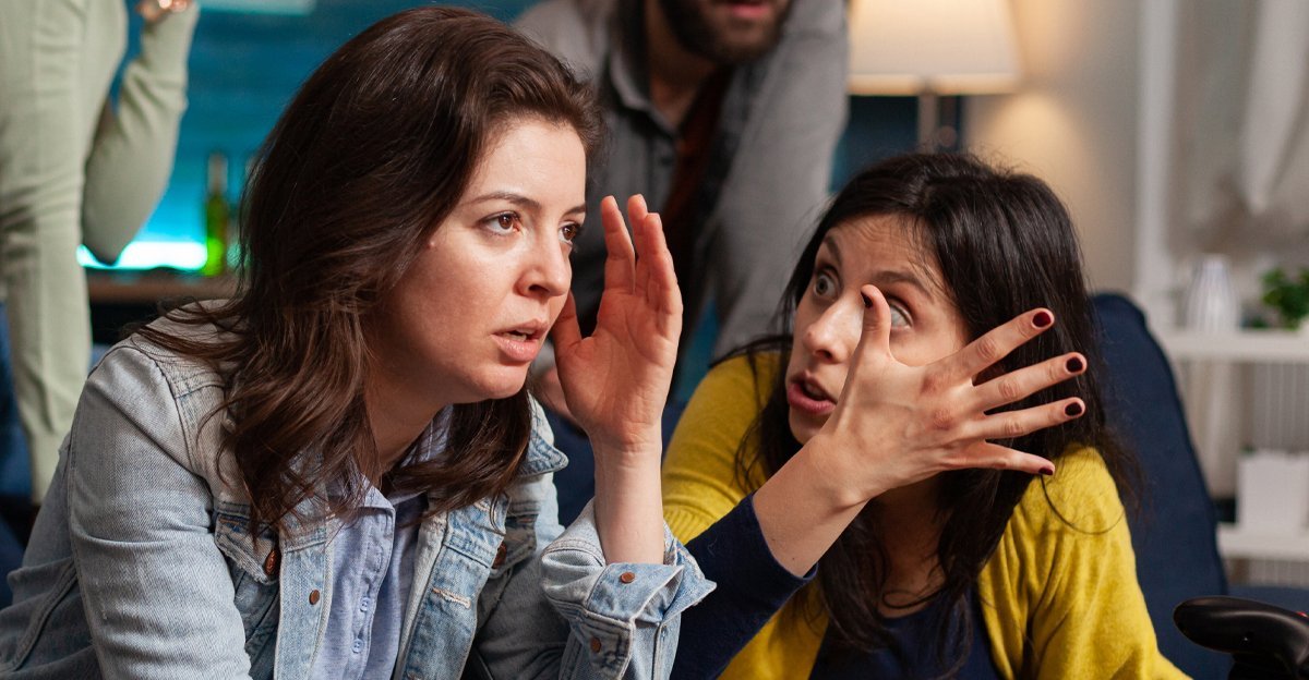 Two women whispering to each other — the miscommunication trope when you brief a designer